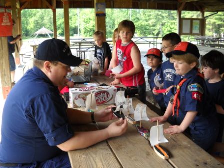 Auxiliarist Wade Love examines the boat built by Tiger Cub Dakota
	Kirker